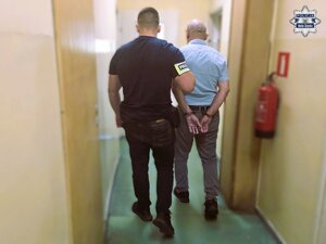 Policjant prowadzi zatrzymanego kierowcę