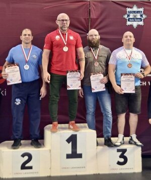 zdjęcie przedstawia policyjnego zapaśnika na podium, obok na niższych stopniach stoją inni zawodnicy