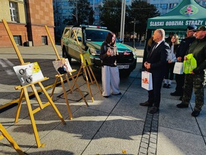 Prezydent i przedstawiciele służb słuchający uczennicy, której prace plastyczne związane z handlem ludźmi zostały wyróżnione