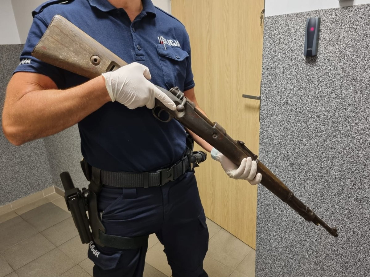 Policjant prezentuje karabin typu Mauser z okresów II Wojny Światowej.