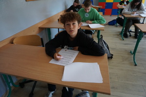Na zdjęciu uczeń szkoły podstawowej pisze test wiedzy.
