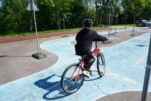 Na zdjęciu uczeń zdający jazdę na rowerze w miasteczku ruchu drogowego.