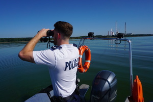 Na zdjęciu policjant patrzący przez lornetki.