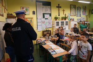 Na zdjęciu policjant ruchu drogowego prowadzi pogadankę z uczniami szkoły podstawowej w Kłokocinie.