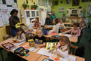 Na zdjęciu pracownica Rybnickich Służb Komunalnych rozdaje dzieciom kamizelki odblaskowe.