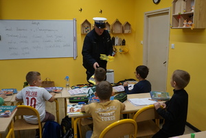 Na zdjęciu policjant z rybnickiej drogówki rozdaje dzieciom odblaski.