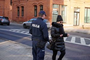 Na zdjęciu policjant z rybnickiej drogówki wręcza kobiecie odblask.