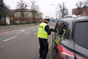 Na zdjęciu policjant nakłada mandat karny kierującemu.