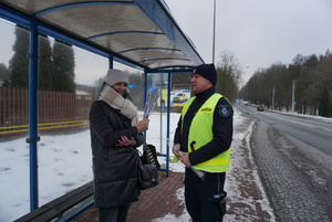 Na zdjęciu policjant rozdający pieszej odblask.