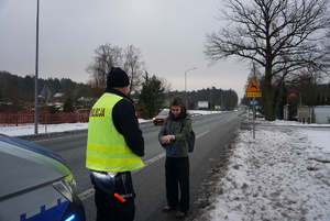 Na zdjęciu policjant rozdający opaskę odblaskową.