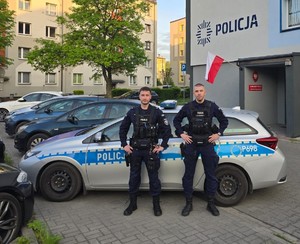 foto przedstawia policjantów na tle radiowozu