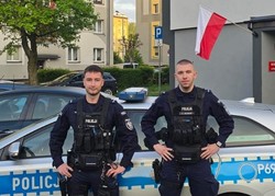 foto przedstawia policjantów na tle radiowozu