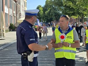 Na zdjęciu naczelnik ruchu drogowego rozmawia z pracownikiem, który kieruje ruchem.