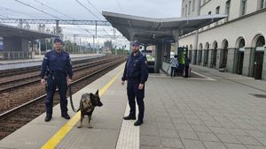 Na zdjęciu dworzec kolejowy oraz policjant, przewodnik psa służbowego oraz funkcjonariusz straży ochrony kolei.