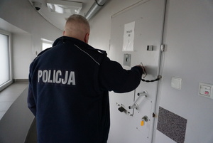 Na zdjęciu policjant w pomieszczeniach dla osób zatrzymanych.