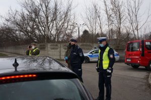 policjanci i wolontariusze fundacji Grot stoją na drodze