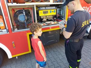 dziecko ze strażakiem przy wozie strażackim