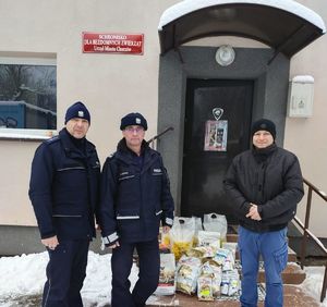 na zdjęciu komendant, policjant, przedstawiciel schroniska i dary