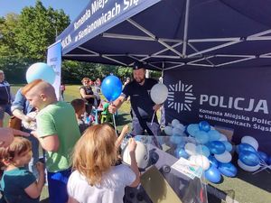 na zdjęciu policjant rozdaje balony dzieciom