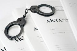 na zdjęciu akta sprawy i kajdanki