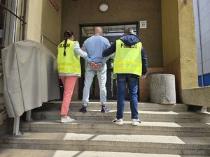 na zdjęciu nieumundurowani policjanci doprowadzają do prokuratury podejrzanego