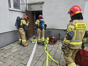 na zdjeciu strażacy wchodzą do budynku