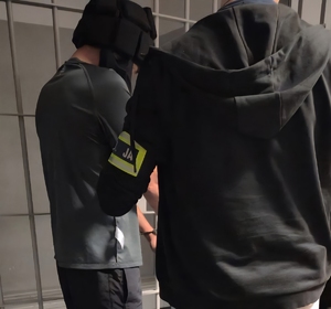 na zdjęciu zatrzymany mężczyzna w kasku ochronnym z policjantem