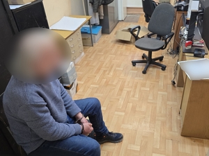 Zdjęcie przedstawia zatrzymanego mężczyznę w trakcie czynności procesowych