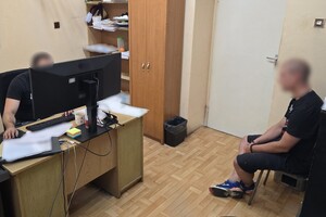 Na zdjęciu widoczny jest zatrzymany mężczyzna w trakcie przesłuchania przez funkcjonariusza dochodzeniowo-śledczego