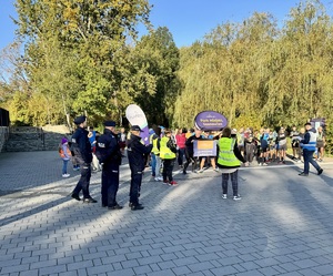 Zdjęcie przedstawia trzech umundurowanych policjantów oraz uczestników biegu na starcie.