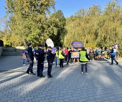 Zdjęcie przedstawia trzech umundurowanych policjantów oraz uczestników biegu na starcie.