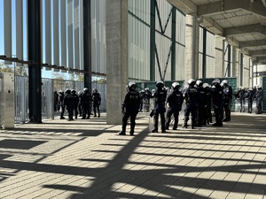 Zdjęcie przedstawia grupę umundurowanych policjantów stojących przy wejściu do obiektu sportowego.