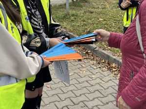 Zdjęcie przedstawia elementy odblaskowe wręczone kobiecie.