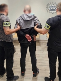 Zdjęcie przedstawia dwóch, nieumundurowanych policjantów z opaskami z napisem &amp;quot;Policja&amp;quot; oraz zatrzymanego mężczyznę.