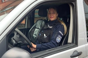 Zdjęcie przedstawia umundurowaną policjantkę, st.sierż. Martę Gałązkę w radiowozie służbowym.