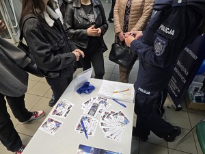Zdjęcie przedstawia umundurowanych policjantów oraz uczestników. W tle ulotki zachęcające do służby w Policji.