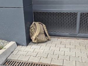 Zdjęcie przedstawia plecak przy garażu.