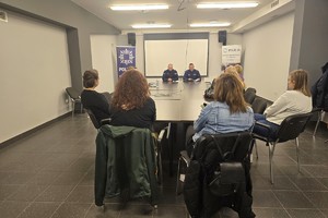 Zdjęcie przedstawia umundurowanych policjantów rozmawiających z uczestniczkami kursu w sali.