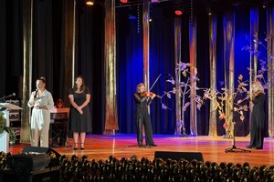 Zdjęcie przedstawia prowadzącą wydarzenie kobietę na scenie.