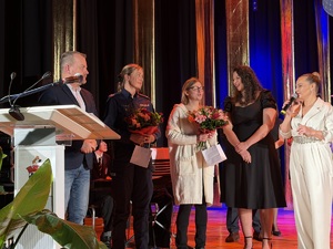 Zdjęcie przedstawia umundurowaną policjantkę oraz uczestników na scenie.