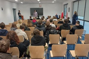 Zdjęcie przedstawia technika kryminalistyki oraz grupę uczniów w sali.