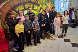 Zdjęcie przedstawia przewodników psów służbowych z uczestnikami spotkania pozujących do zdjęcia.