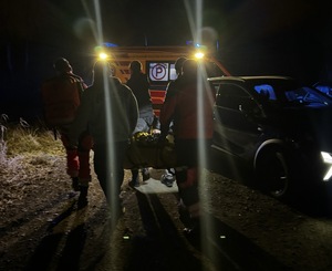 Ratownicy medyczni z zaginionym. W tle karetka.