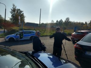 Policjanci z Wydziału Ruchu Drogowego KMP Świętochłowice podczas oczekiwanie na sprawdzenie kontrolowanego pojazdu. W tle ekipa TVP1 w trakcie nagrania.