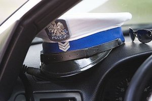Na zdjęciu Czapka z białym otokiem policjanta z drogówki leżaca na kokpicie wewnątrz pojazdu