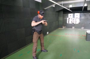 Na zdjęciu instruktor wyszkolenia strzeleckiego ze świętochłowickiej komendy, który trzyma w dłoniach broń i pokazuje uczestnikom technike sprawdzania broni po odaniu strzału