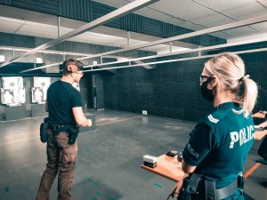 Na zdjęciu umundurowana policjantka słucha instruktora który objaśnia ćwiczenia doskonalące technikę strzelecką