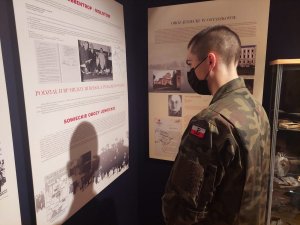 Na zdjęciu uczeń w umundurowaniu wojskowych podczas zwidzania pomieszczenia Izby Pamięci i jej wystawy