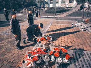 Na zdjeciu troje uczniow w poczcie honorowy podczas skadania kwiatów na Grobie Policjanta Polskiego podczas oddawnia hołdu ludziom, którzy poświęcili życie dla dobra Ojczyzny.