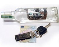 na zdjęciu szklana butelka po alkoholu, kluczyki i dowód rej.